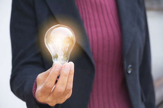 Hand of businesswomean holding light bulb for idea or success or solar energy