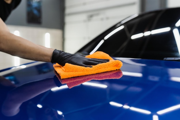 Foto asciugatura manuale dell'auto con microfibra nei dettagli del servizio automatico auto addetto alle pulizie con carrozzeria asciutta dopo il lavaggio dell'automobile