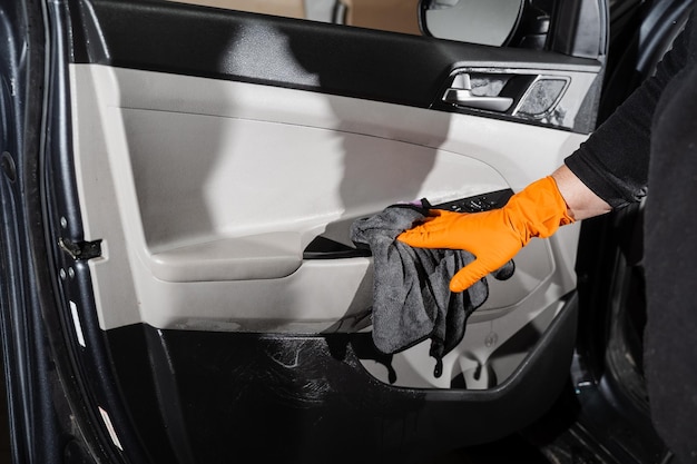 Hand car interior drying of car door card panel using microfiber in detailing auto service Cleaner worker dry car interior