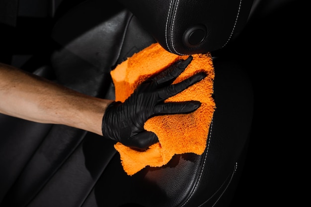 Hand car interior drying of leather seat using microfiber in detailing auto service Cleaner worker dry car interior