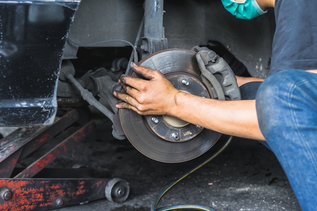 Photo hand of car mechanic fixing disc brakes, car maintenance in the professional service.