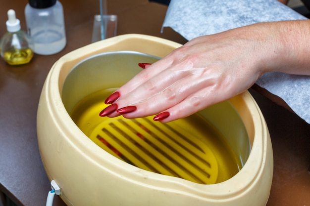 Hand care with hot wax, covering with wax, manicure salon.