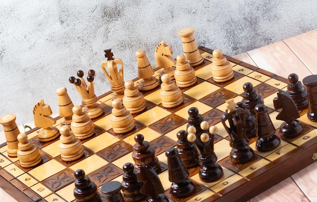 Hand-carved chess pieces on a handcrafted wooden chessboard. Business strategy, tactics concept