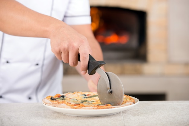 Foto lo chef a mano sta preparando una pizza al kithen.