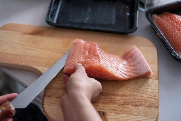 Шеф-повар, используя нож ломтик сырого лосося на разделочную доску