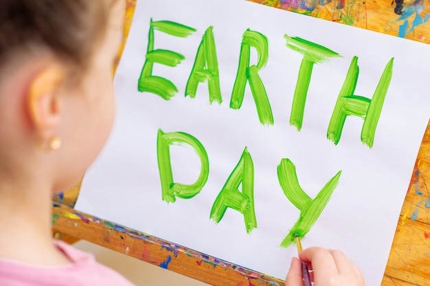 Hand of child drawing word Earth Day