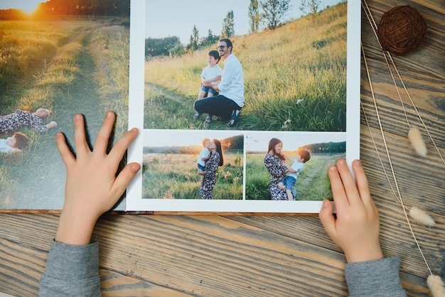 木製のテーブルの家族の写真アルバムを保持している手の子供