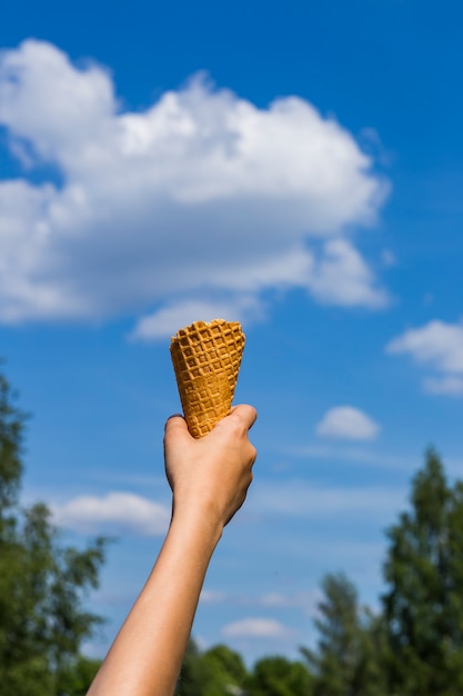  the hand of the child, there is a cone for ice cream and a cloud in the sky