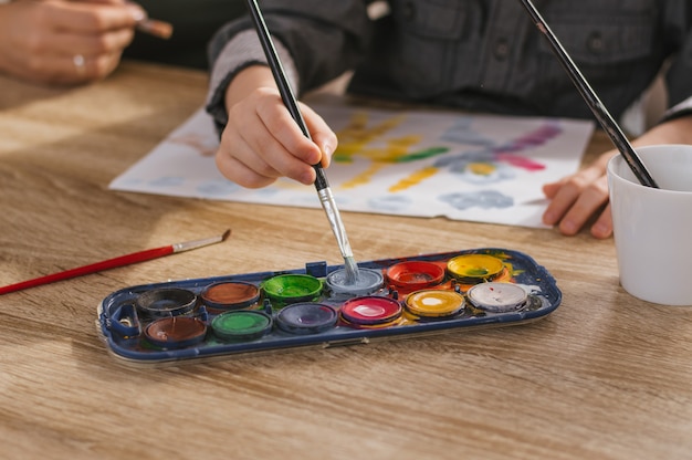 Photo hand of child using brush and watercolor