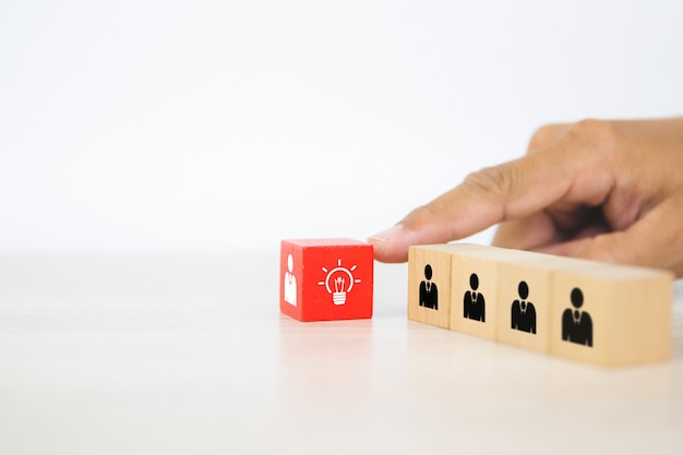 Hand choose human with light bulb icon on cube wooden block stack.