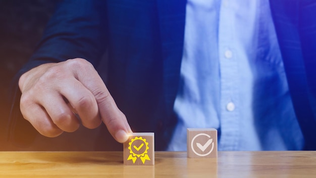 アイコン付きの木製キューブブロックを手で選ぶ 品質保証管理基準 最高のサービスの兆候を示します 品質保証保証基準 ISO認証と標準化の概念