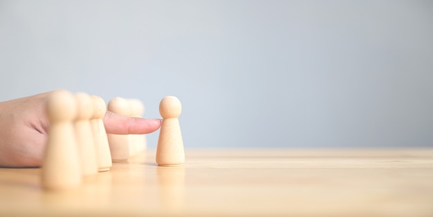 Hand chooses a wooden people standing out from the crowd