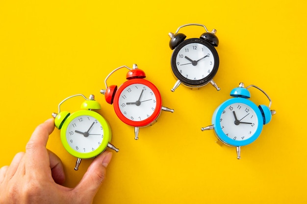 Hand choosing a green alarm clock