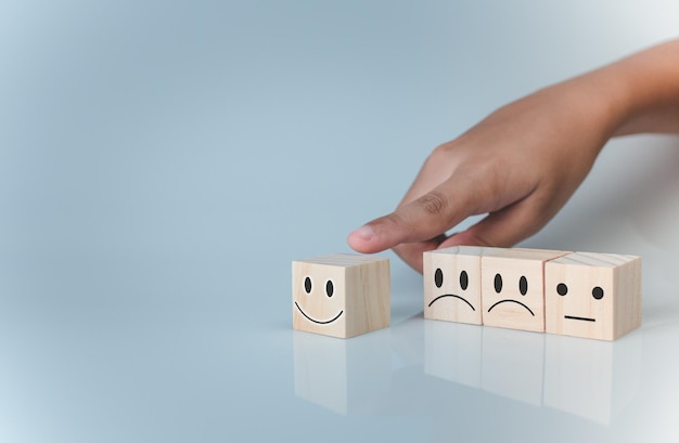 Hand choosing happy smile icon represents feedback rating and positive customer review .