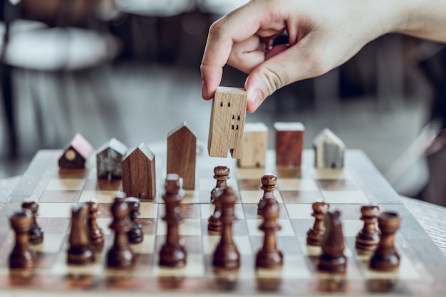 Рука, выбирая мини-модель деревянного дома из шахматной игры, Выберите, что лучше.