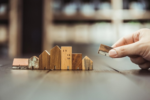 Photo hand choosing mini wood house model from model and row