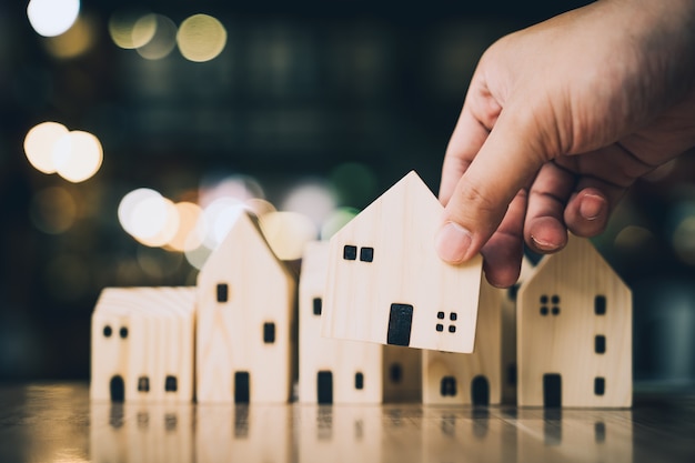 Hand choosing mini wood house model from model