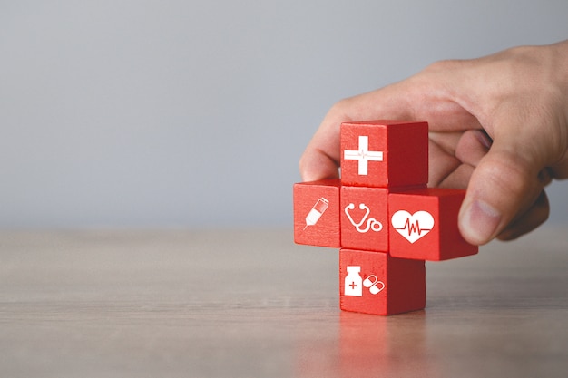 Hand choosing wood cube with icon medical,insurance concept.