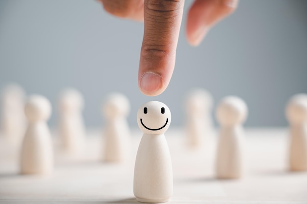 Photo hand choosing a wooden figure as the chosen leader from the crowd