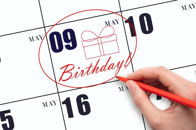 The hand circles the date on the calendar 9 May draws a gift box and writes the text Birthday Holiday