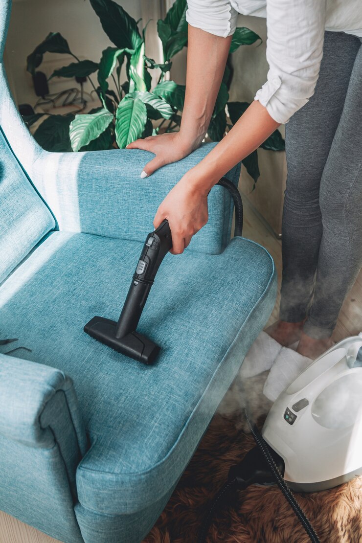 Photo hand cleaning an armchair with a steam cleaner