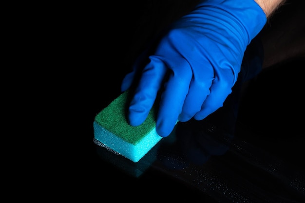 Hand cleaning black desk with a blue washcloth Close up shot of a home cleaning process