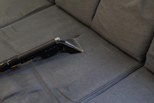 Hand cleaning a sofa with a steam cleaner, Home cleaning concept.