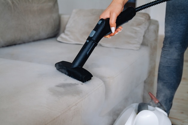 Hand cleaning a sofa with a steam cleaner