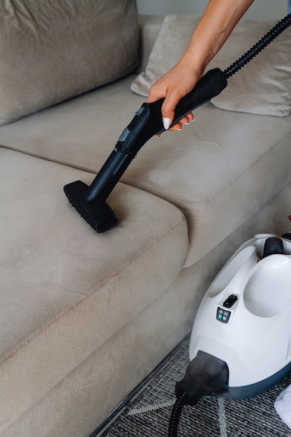 Photo hand cleaning a sofa with a steam cleaner