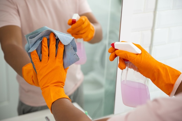 Hand cleaning up the mirror using cloth and spray