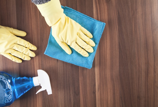 Hand cleaning wooden table at home.