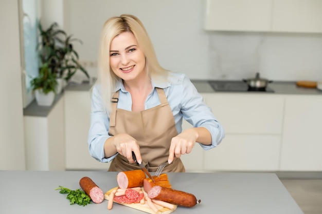 Рука крупным планом режет салями кусочками за столом