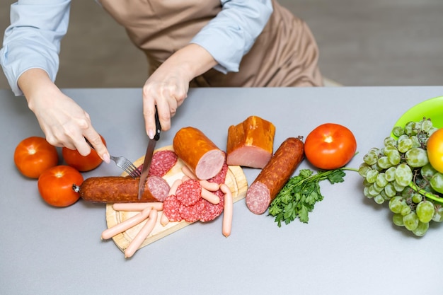 Hand closeup cuts salami with slice pieces at table