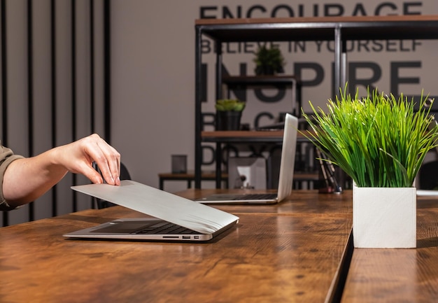 Hand closing lid cover of laptop in office Ending finishing work day concept