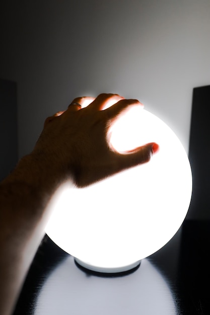 Foto una mano che stringe una sfera di luce bianca spaventosa per halloween.