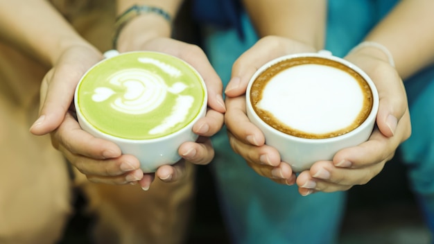 手とコーヒーと熱い緑茶若者は熱い飲み物を飲むのが大好きです。