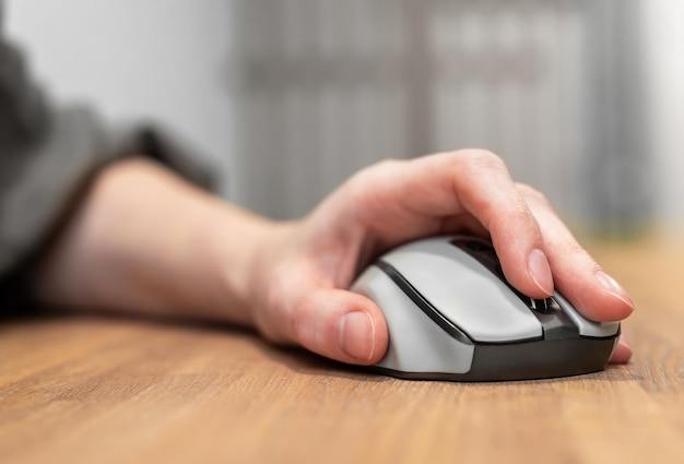 Hand on computer mouse on wood table wooden office desk Browsing surfing internet search query concept