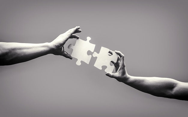 Hand connecting jigsaw puzzle. Business solutions, success and strategy concept. Man hands connecting couple puzzle piece. Business solutions, target, success, goals and strategy concepts