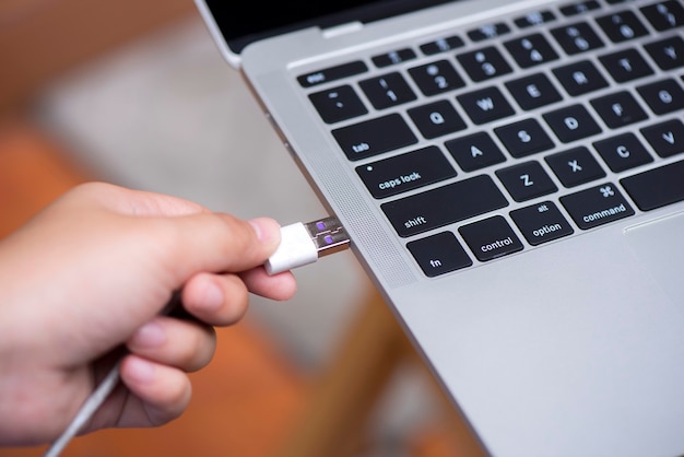 Photo hand connecting usb cable to laptop computer