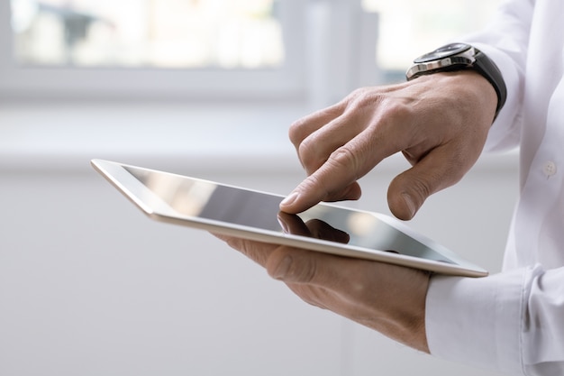 Рука современного бизнесмена с планшетом, указывая на экран во время презентации или прокрутки онлайн-данных