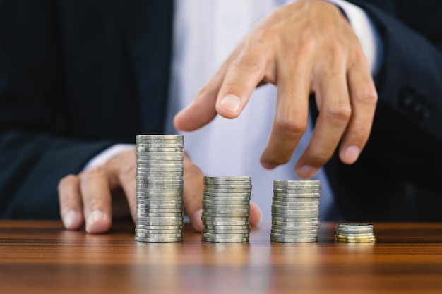 Hand counting coins stack on wooden table, Cons stack saving money or investment concept, Coin in business finance invest concept