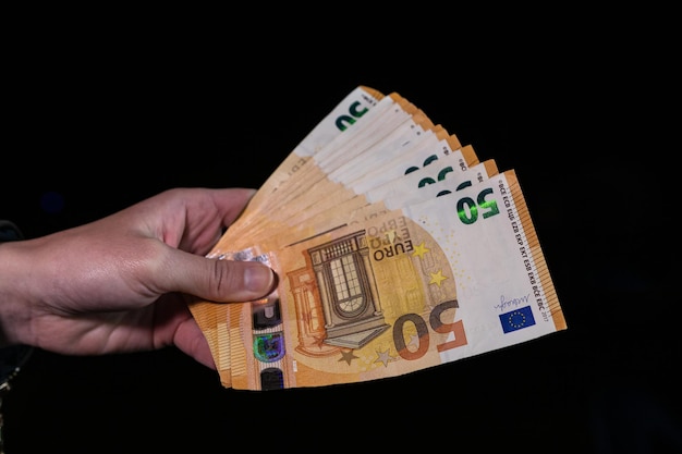 手を数えて、ユーロのお金を持って見せたり、お金を与えたりします。世界のお金の概念、コピー スペースと黒に分離された 50 ユーロ紙幣ユーロ通貨。金持ち、お金を節約または支出の概念