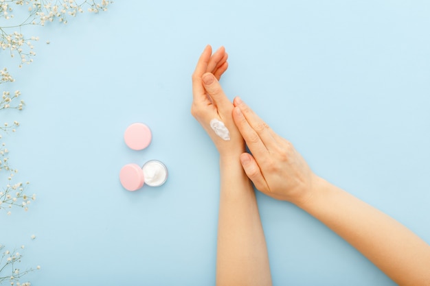 Foto crema per le mani, mani femminili che applicano cosmetici crema naturali biologici. crema per la cura della pelle in barattolo per mani, corpo