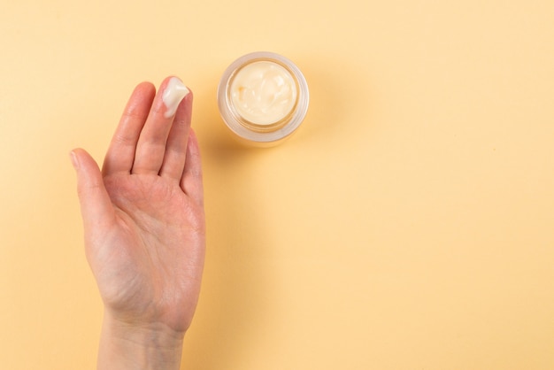 Hand cream and woman hands on a beige background.