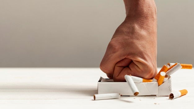 Photo hand crushing pack of cigarettes