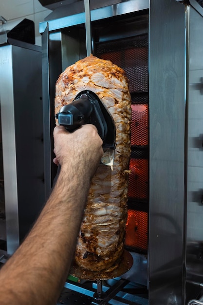 Foto taglia a mano il kebab con una tagliatrice