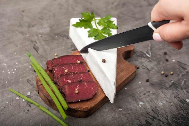柔らかいチーズを白いカビで手でカットします。まな板に詰まった肉