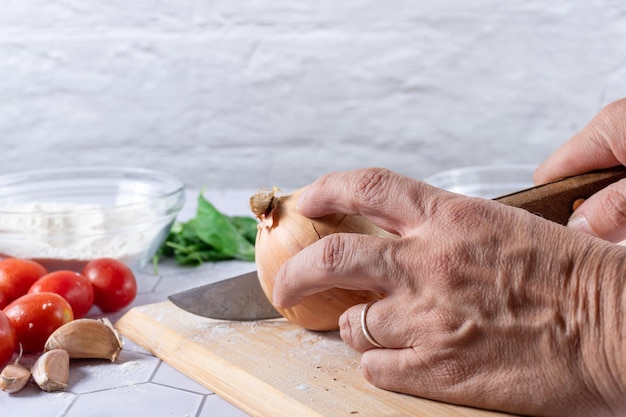 A hand cutting onion between ingredients and kitchen tools