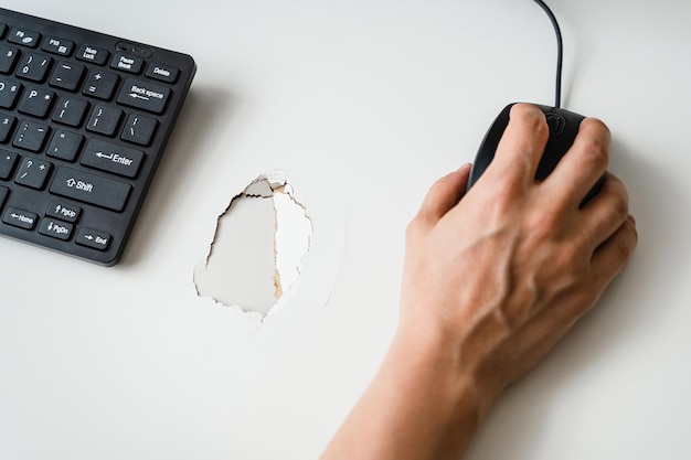 Hand and damaged desk with hole inside Concept of stressful work