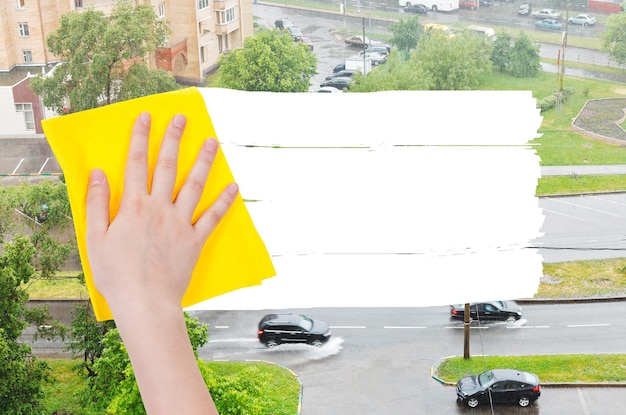 Foto la mano elimina la pioggia sulla strada con uno straccio giallo